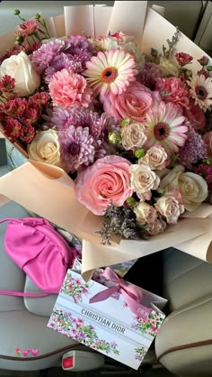 a bouquet of flowers sitting on top of a car seat in front of a card