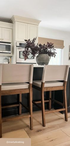 a kitchen with white cabinets and black countertops has a vase filled with flowers on the island