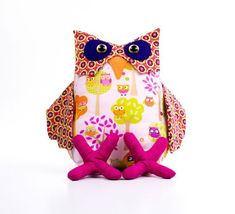 an owl stuffed animal sitting on top of a white floor next to two pink legs