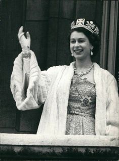 an old black and white photo of a woman wearing a tiara with her arms in the air