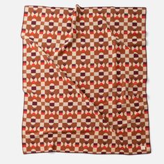 a brown and red checkered blanket with an orange design on it