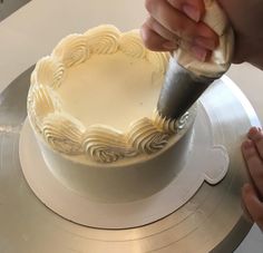 someone is decorating a white cake with icing