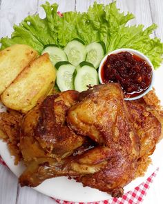 a white plate topped with meat and veggies on top of a red and white checkered table cloth