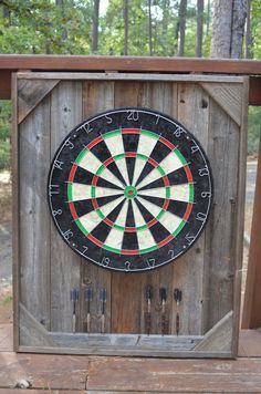 a close up of a dart board on a wooden fence with trees in the background