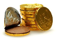 a pile of gold coins next to a chocolate cookie