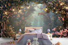 a bedroom decorated with fairy lights and teddy bears in front of a forest wall mural