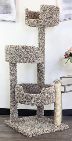 a cat scratching tower in the corner of a room with a flower vase on the floor