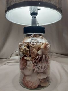 a glass jar filled with sea shells under a lamp