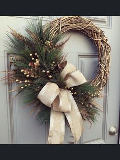 a wreath with pine cones and berries hanging on a door