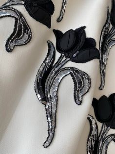 black and white fabric with silver sequins on the edges, featuring an image of a flower