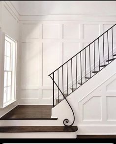 an empty room with white walls and black railings on the stair case, along with wood flooring