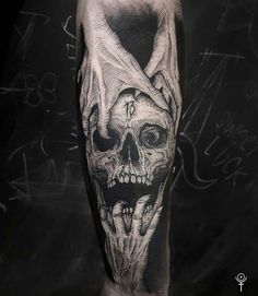 a man's leg with a black and white tattoo design on it, including a skull