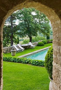 an open doorway leading into a lush green yard with lawn chairs and pool in the distance