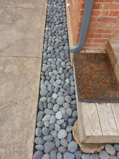 a walkway made out of rocks next to a brick wall