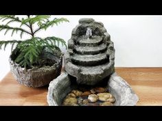 there is a small fountain in the middle of some rocks and plants next to it