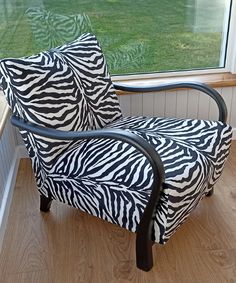 a zebra print chair sitting in front of a window next to a grass covered field