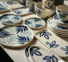 a table topped with lots of blue and white plates covered in leafy designs on them