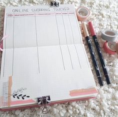 an open planner and some pens on a white carpet