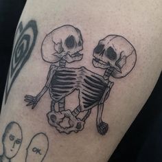 a couple of skulls sitting on top of each other's legs with one holding the other