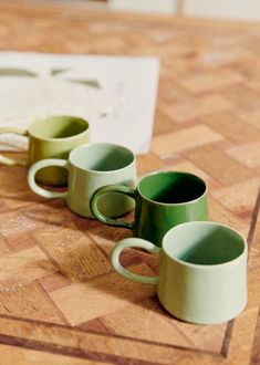 four green cups sitting on top of a wooden table