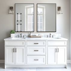 two mirrors are above the double sinks in this bathroom with white cabinets and marble countertops