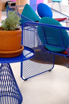 several different colored chairs and tables with plants on them in a room filled with furniture