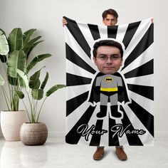 a man holding up a black and white towel with the image of batman on it