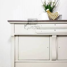 a white painted dresser with flowers on top