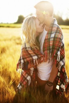 a man and woman are kissing in the middle of a field with sun shining on them