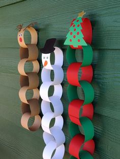 three paper christmas wreaths hanging on a green wooden wall with snowmen and trees