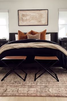 a bedroom with a bed, two chairs and a painting on the wall above it