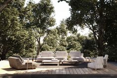 a couch and chairs sitting on top of a wooden deck next to some green trees