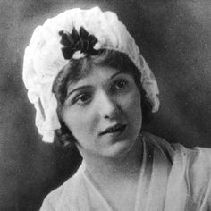 an old black and white photo of a woman wearing a hat with flowers on it