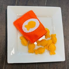 a white plate topped with an orange and white dessert next to some yellow candies