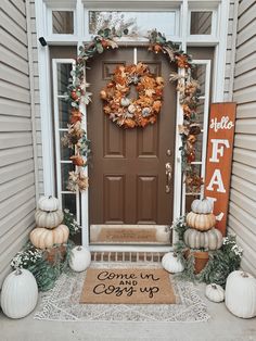 a front porch decorated for fall with pumpkins and gourds