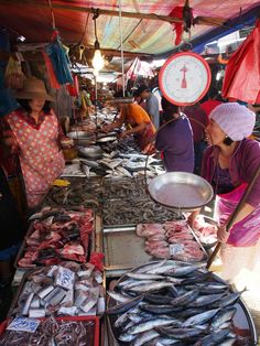 people are shopping at an outdoor market with fish