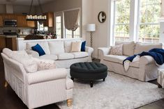 a living room filled with white furniture and lots of pillows on top of it's couches