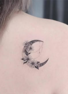 a woman's back shoulder with a crescent and flowers tattoo