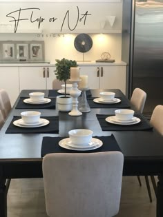 a dining room table set with white dishes and black placemats, next to a refrigerator