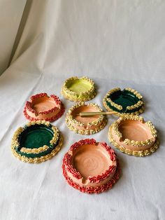 several small bowls and spoons are sitting on a white tablecloth with gold trim