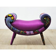 a purple chair with colorful designs on it sitting on a wooden floor next to a white wall