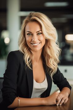 a woman sitting at a table with her arms crossed and looking into the camera, smiling