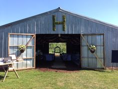 an open barn with tables and chairs set up for a wedding reception on the lawn