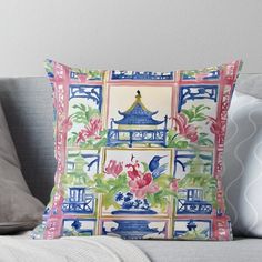 a decorative pillow on a couch in front of a wall with flowers and pagodas