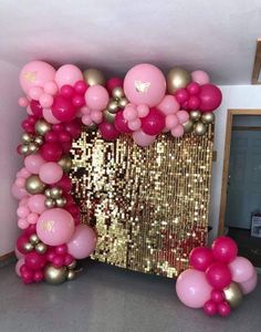 a pink and gold balloon arch in the middle of a room