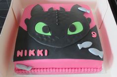 a birthday cake in the shape of a dragon with green eyes and pink icing