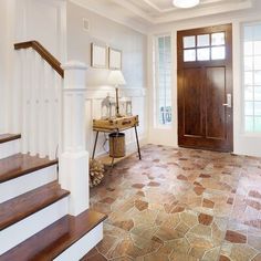 a foyer with stone flooring and wooden door leading up to the second story area