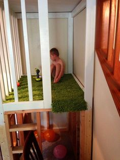 a boy sitting on the ground in a room with green carpet and grass flooring