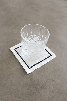 a clear glass on a black and white napkin