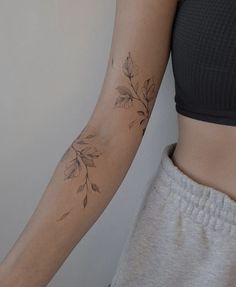 a woman's arm with leaves on it and a tattoo design on the wrist